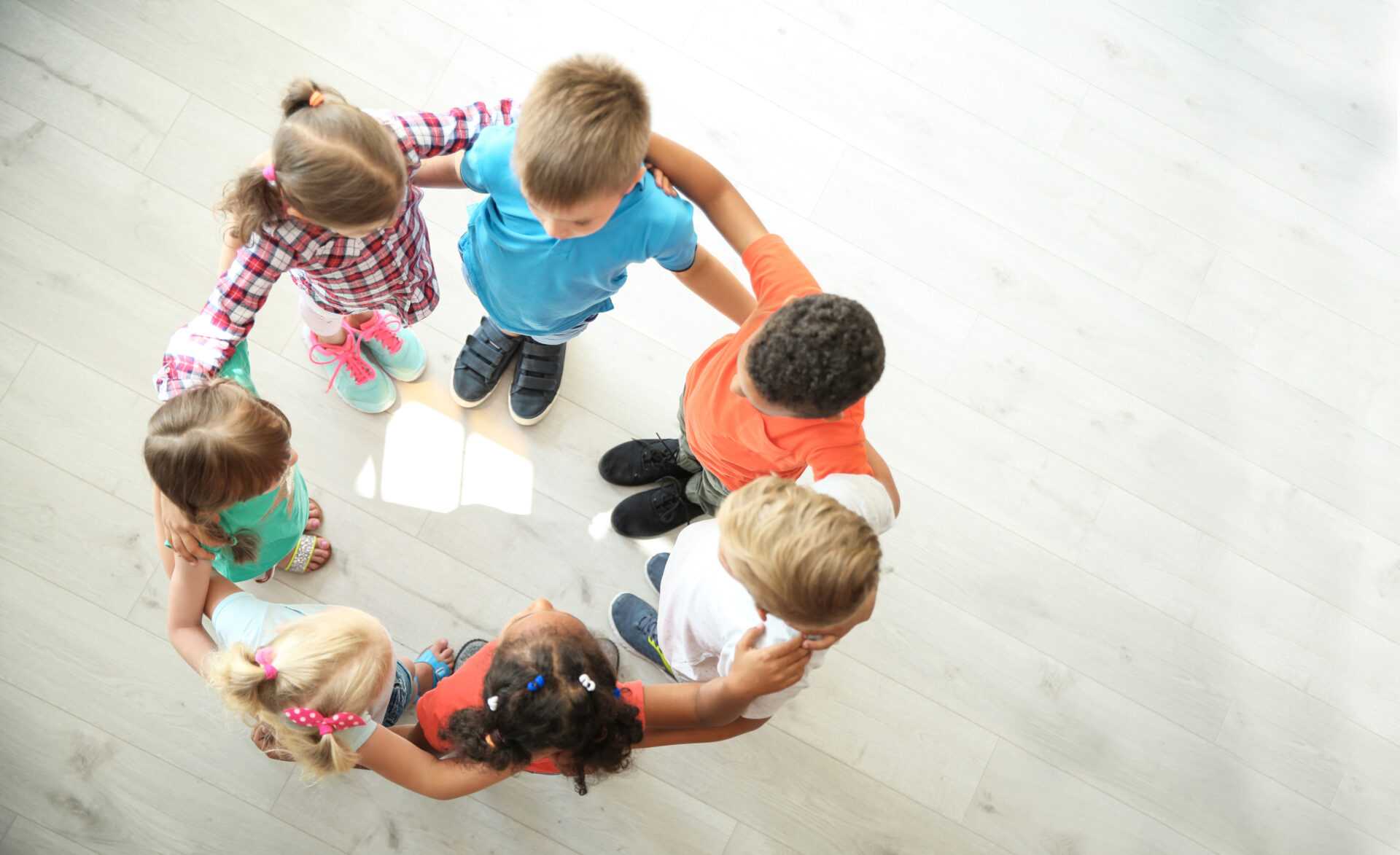 Little children making circle with hands around each other indoors, top view.