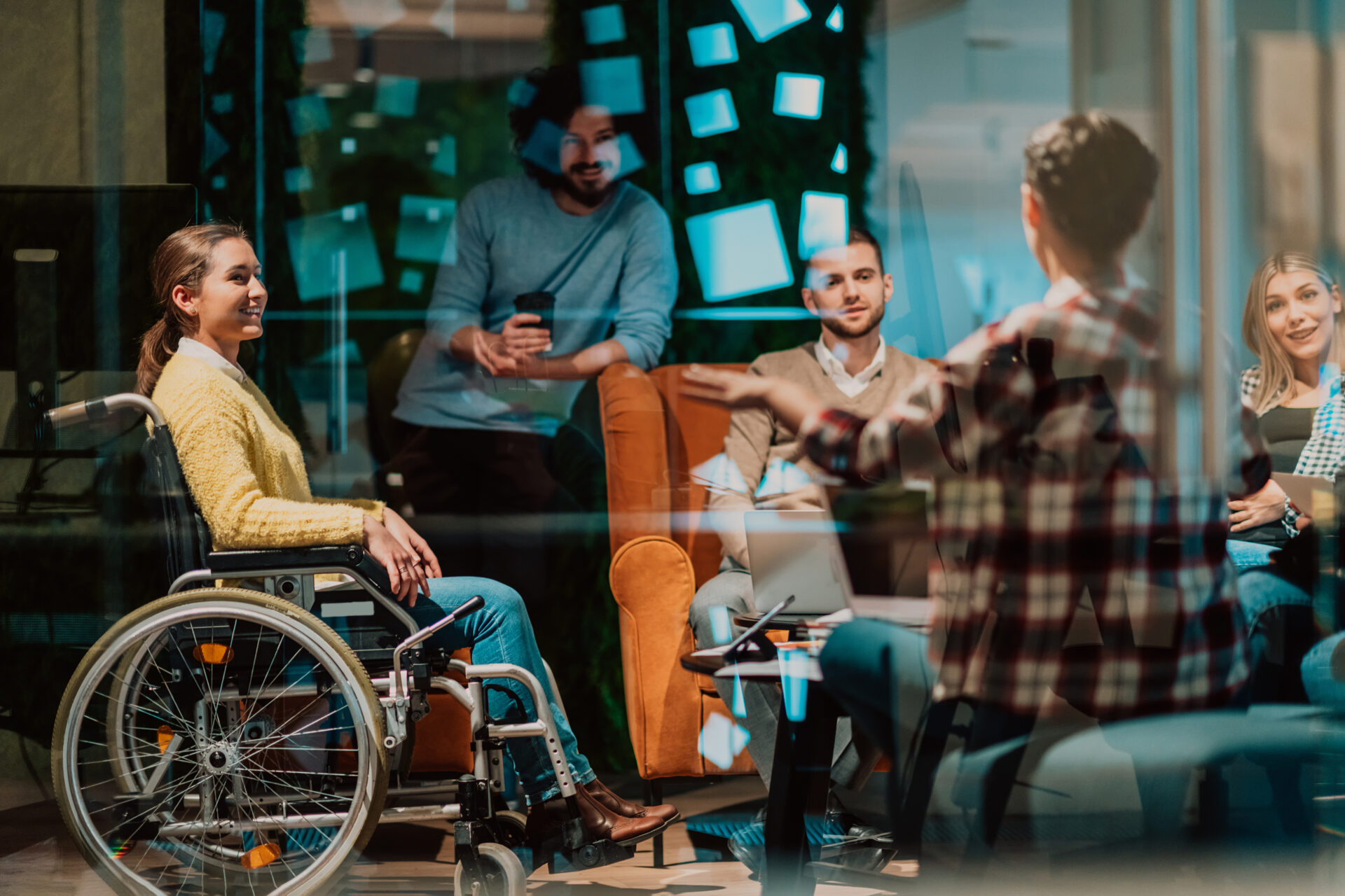 A businesswoman in a wheelchair having a business meeting with the team at a modern office.