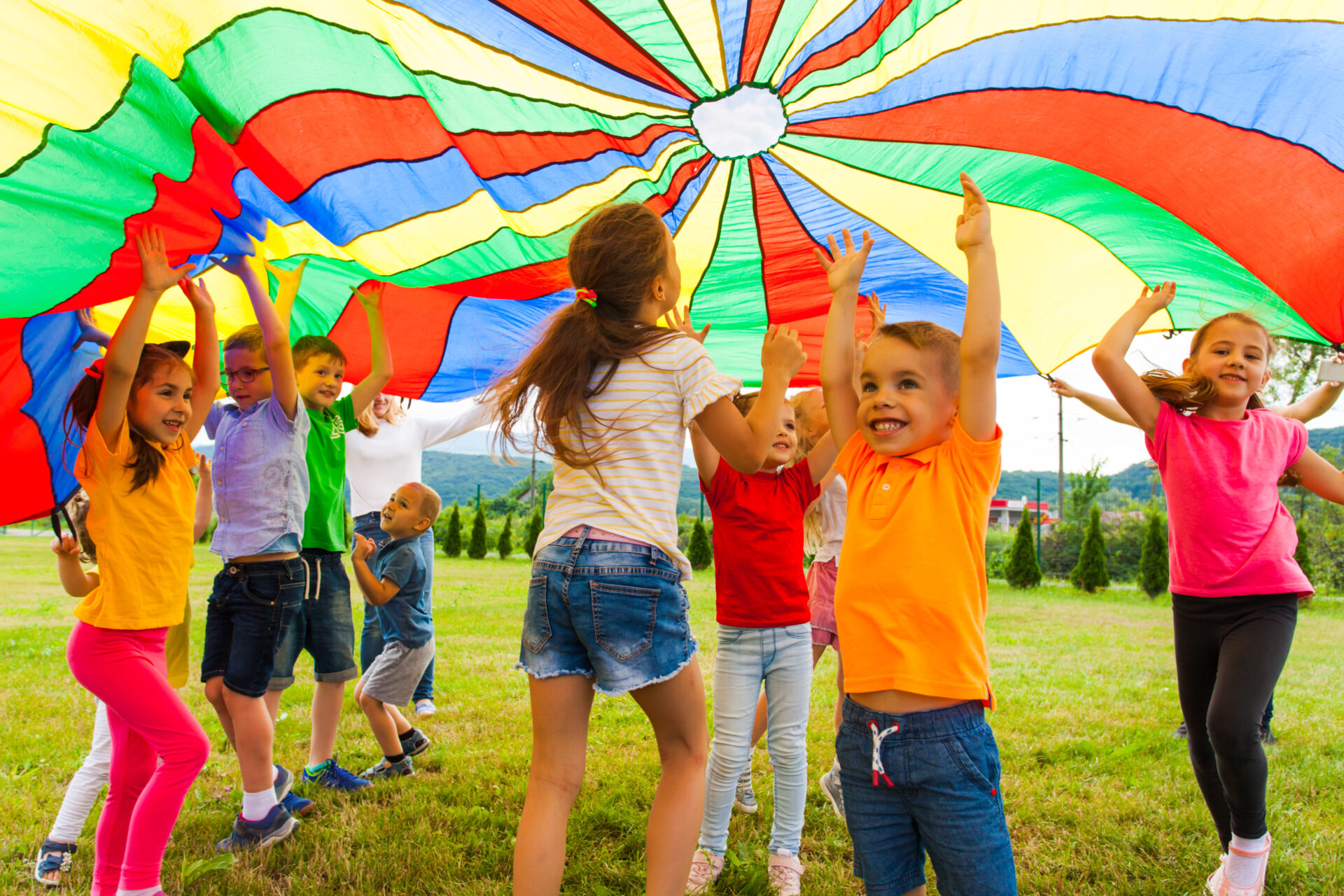a group of children holding onto a colorful kite